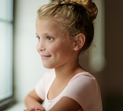 Quinn is smiling while looking out the window during ballet rehearsal.