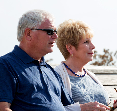 An older couple stands next to each other and looks into the distance